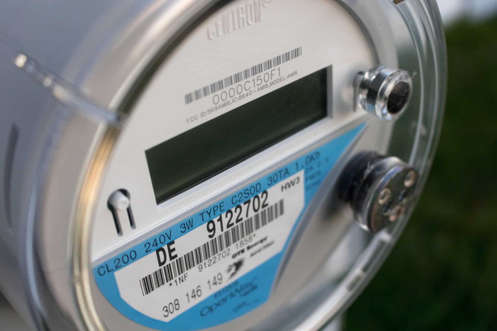 Gros plan sur un compteur électrique intelligent moderne, montrant un écran numérique, des codes-barres et des numéros d'identification sur son boîtier argenté.